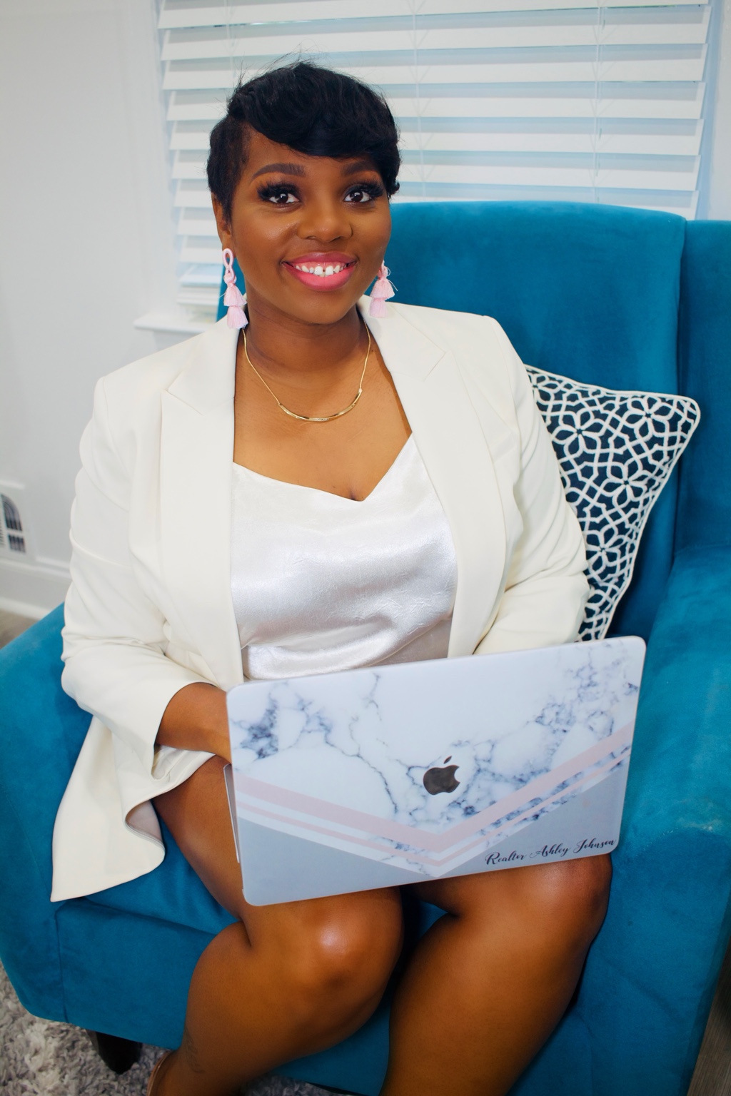 Business owner in a white suit holding a laptop for her professional portrait