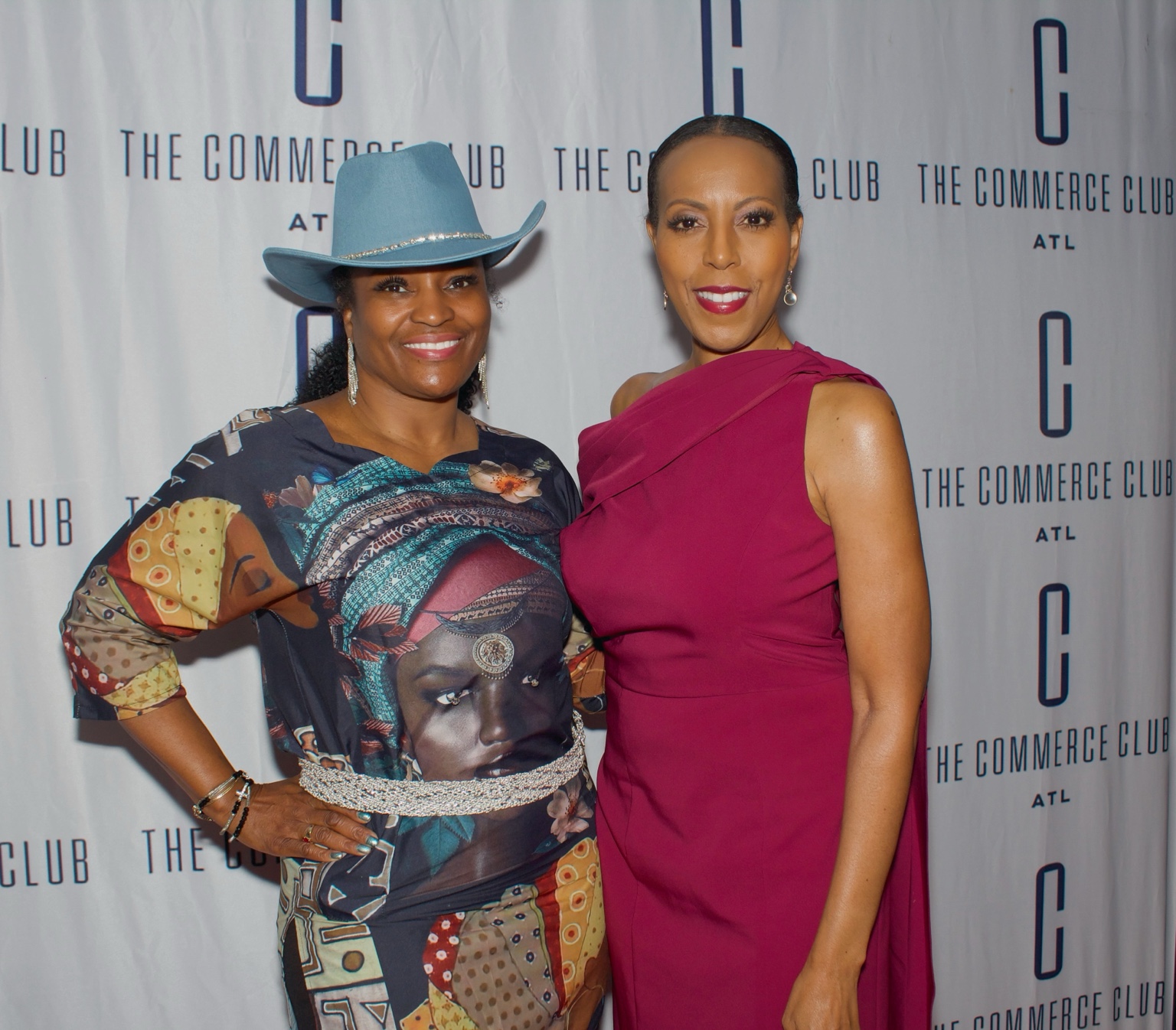 Two women at a business gathering in front of a Commerce Club backdrop