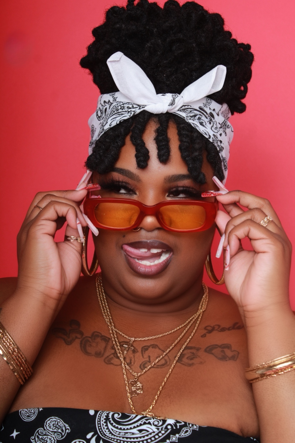 Creator adjusting orange sunglasses in a colorful portrait
