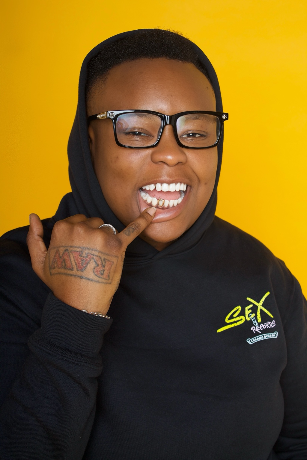 Smiling music creative in black against a vivid yellow backdrop