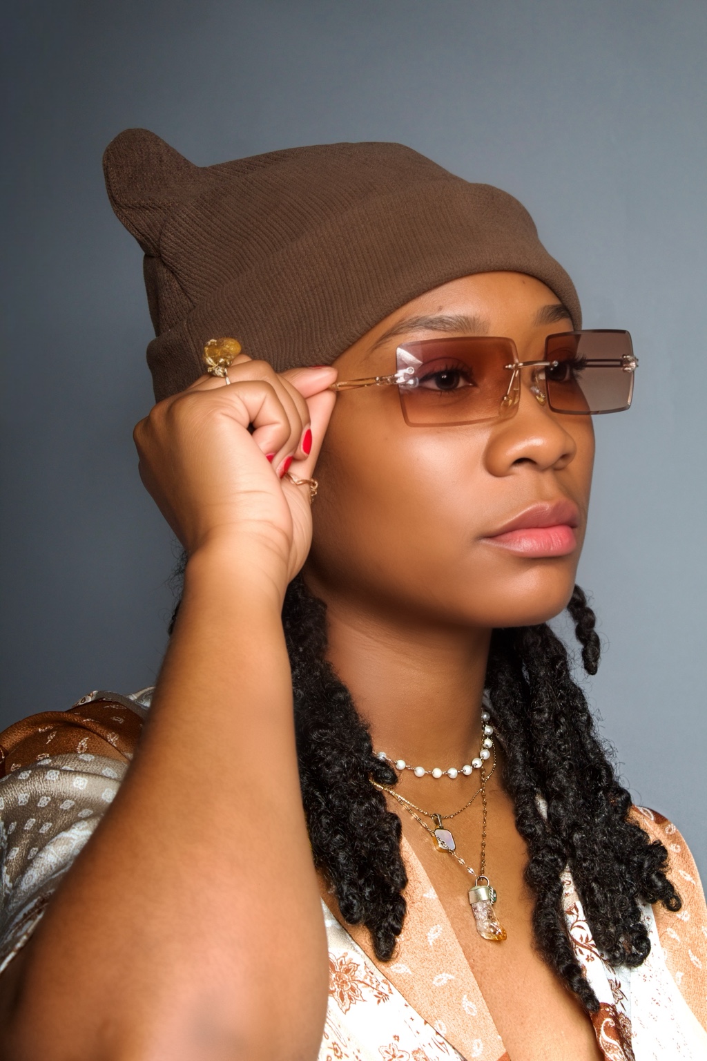 Creative portrait of a woman with locs, a brown beanie, and tinted sunglasses by Ki Shot It Visuals